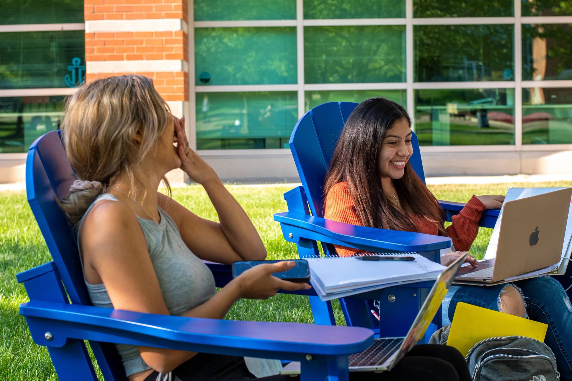 students in the sunlight lounging in lanwn chairs
